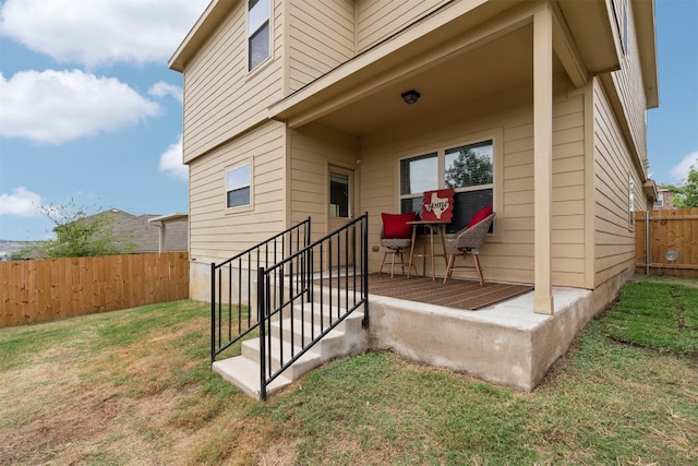 view of exterior entry featuring a lawn and a patio area