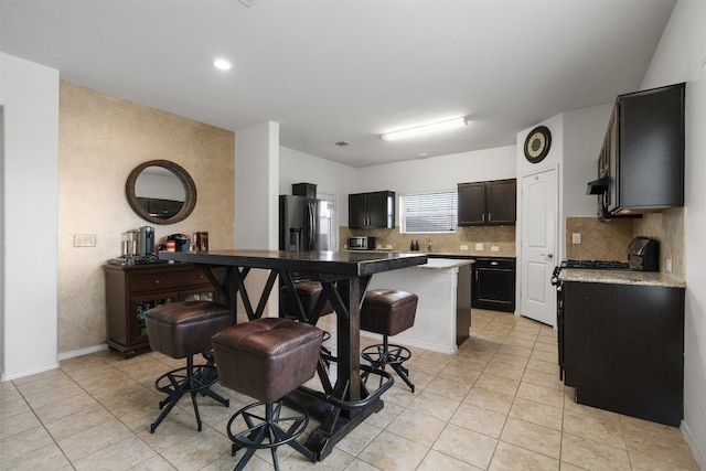 kitchen featuring stainless steel refrigerator with ice dispenser, decorative backsplash, light tile patterned floors, range hood, and a kitchen island