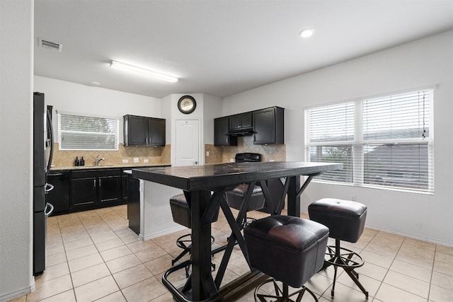 kitchen with sink, tasteful backsplash, stainless steel refrigerator, and light tile patterned flooring