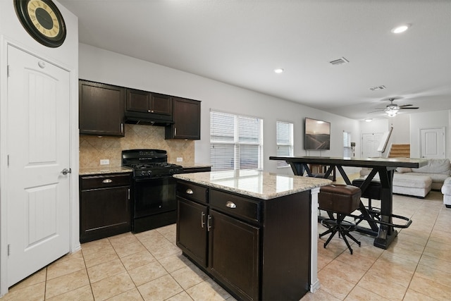 kitchen with ceiling fan, black gas stove, a center island, and light tile patterned floors