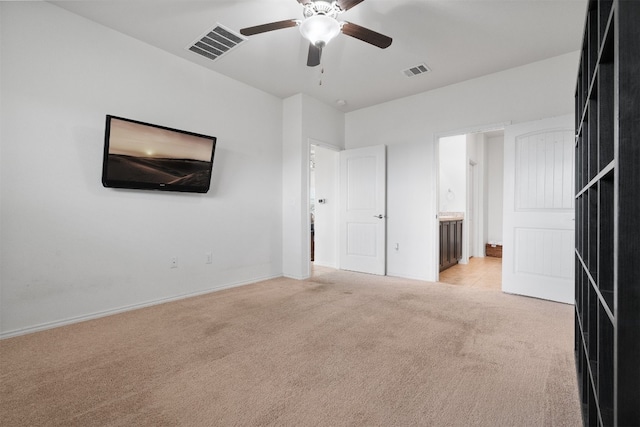 interior space featuring light colored carpet, ensuite bath, and ceiling fan