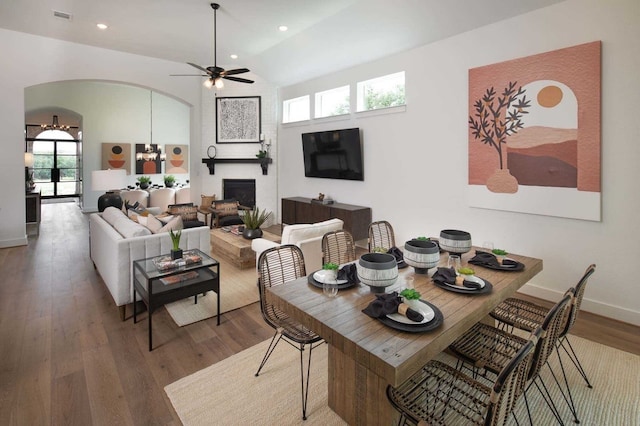 dining space featuring hardwood / wood-style flooring, vaulted ceiling, and a fireplace