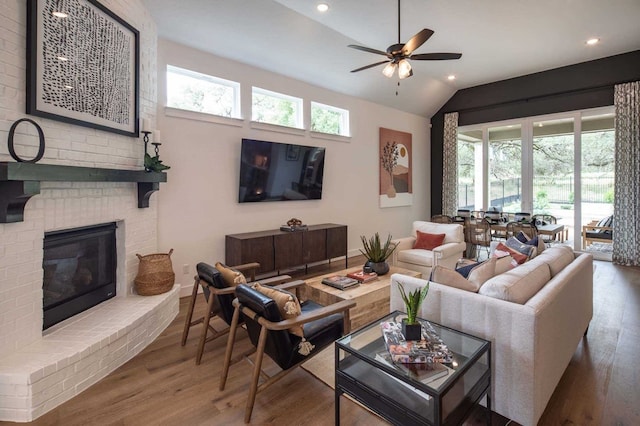 living room featuring hardwood / wood-style floors, a fireplace, a healthy amount of sunlight, and vaulted ceiling