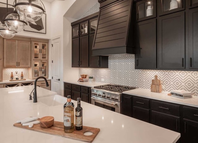 kitchen with pendant lighting, stainless steel range, custom exhaust hood, and backsplash