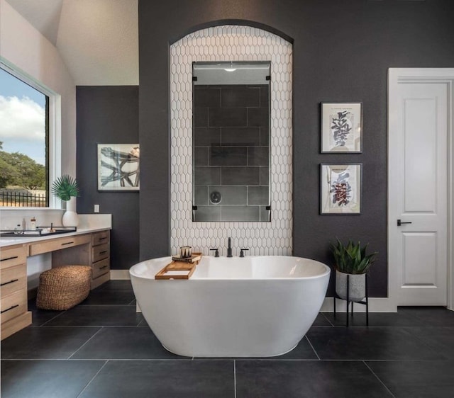 bathroom featuring tile patterned flooring, vanity, vaulted ceiling, and a bathing tub