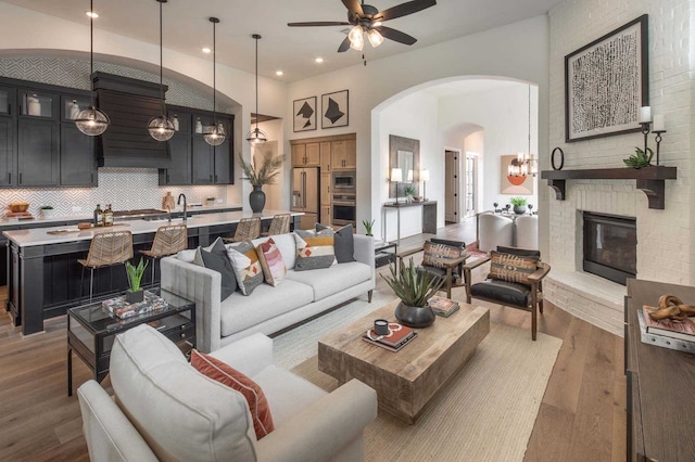 living room featuring a fireplace, wood-type flooring, sink, and ceiling fan