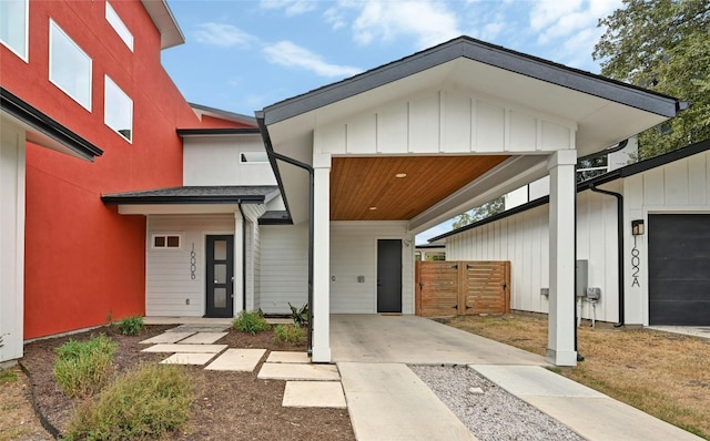 contemporary home featuring a carport, board and batten siding, and fence