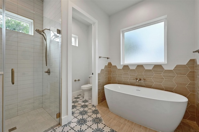 bathroom featuring toilet, a wealth of natural light, and separate shower and tub