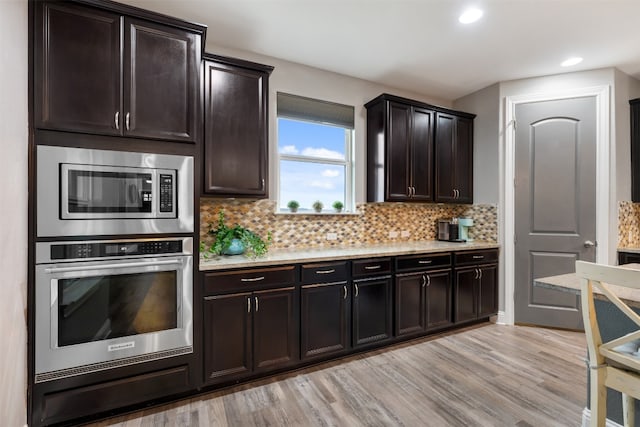 kitchen with stainless steel appliances, dark brown cabinetry, decorative backsplash, and light wood-type flooring