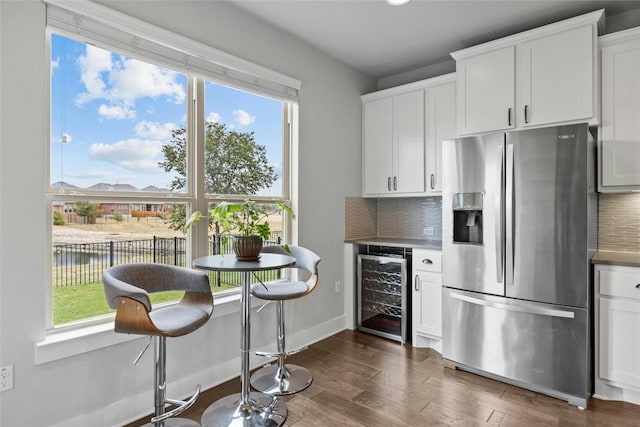 kitchen featuring white cabinets, stainless steel fridge, plenty of natural light, and wine cooler