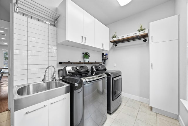 laundry area with sink, cabinets, washing machine and clothes dryer, and light tile patterned flooring