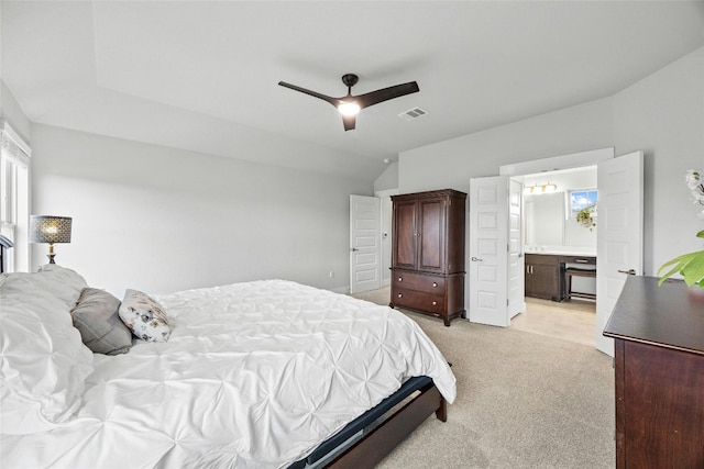 carpeted bedroom with ensuite bathroom, lofted ceiling, and ceiling fan