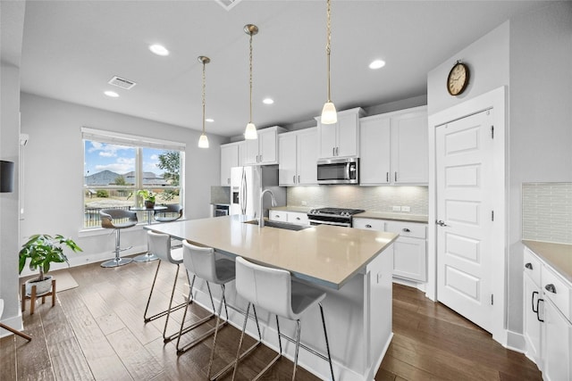 kitchen with appliances with stainless steel finishes, sink, an island with sink, and white cabinets