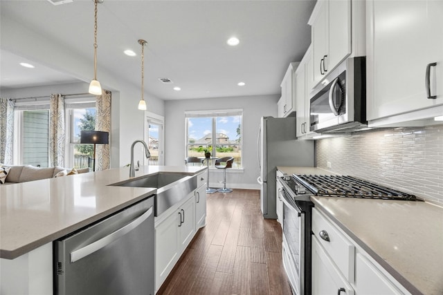 kitchen featuring stainless steel appliances, dark hardwood / wood-style flooring, white cabinets, hanging light fixtures, and sink