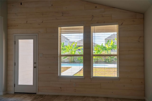 entryway featuring wooden walls, wood-type flooring, and lofted ceiling