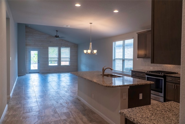 kitchen with decorative light fixtures, light stone countertops, stainless steel range with gas cooktop, vaulted ceiling, and a kitchen island with sink