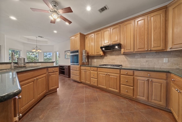 kitchen with sink, appliances with stainless steel finishes, ceiling fan with notable chandelier, backsplash, and pendant lighting