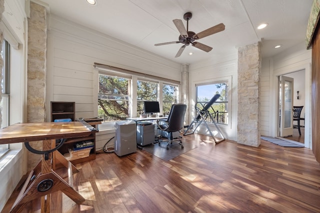 office area featuring dark wood-type flooring, ceiling fan, wooden walls, and a healthy amount of sunlight