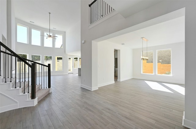 7701 Becasseau Dr, Austin, TX 78738 - unfurnished living room with a ceiling fan, healthy amount of natural light, a chandelier, wood finished floors, and a towering ceiling