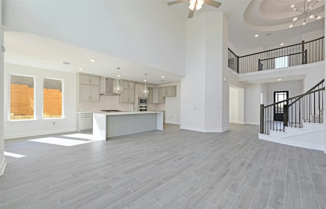 7701 Becasseau Dr, Austin, TX 78738 - unfurnished living room with a towering ceiling, stairway, recessed lighting, light wood-style floors, and ceiling fan