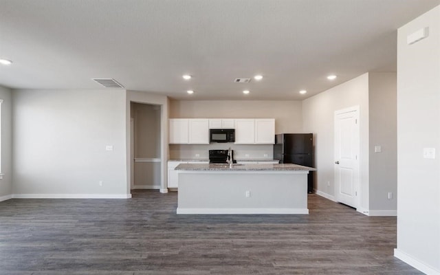 kitchen with black appliances, a center island with sink, white cabinetry, light stone countertops, and dark wood-type flooring