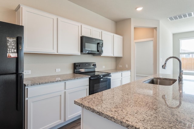 kitchen with black appliances, white cabinetry, sink, and light stone counters