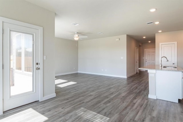 unfurnished living room with dark wood-type flooring, ceiling fan, and sink