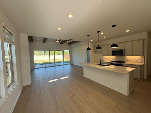 kitchen featuring ceiling fan, light hardwood / wood-style flooring, beamed ceiling, pendant lighting, and black range