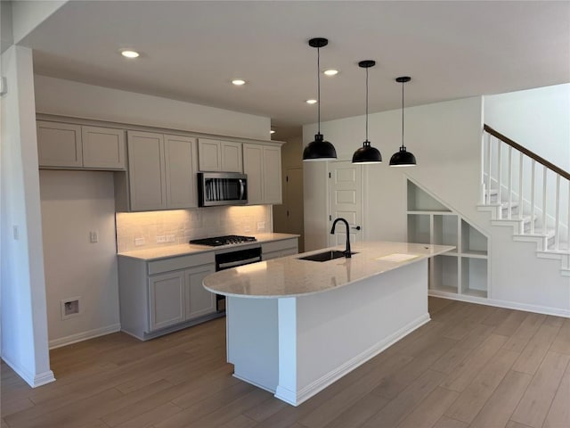 kitchen featuring backsplash, hanging light fixtures, sink, light stone countertops, and appliances with stainless steel finishes