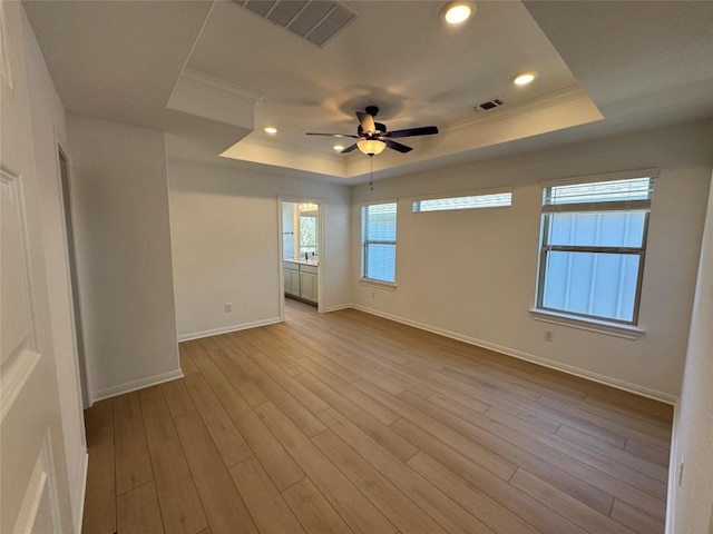 unfurnished room with a tray ceiling, ceiling fan, and light hardwood / wood-style floors