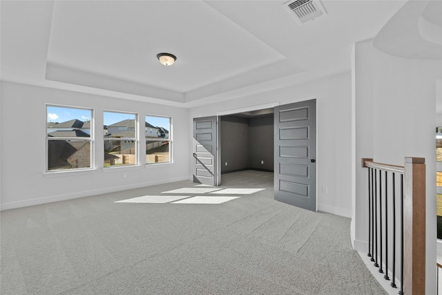 unfurnished bedroom featuring a tray ceiling and carpet floors