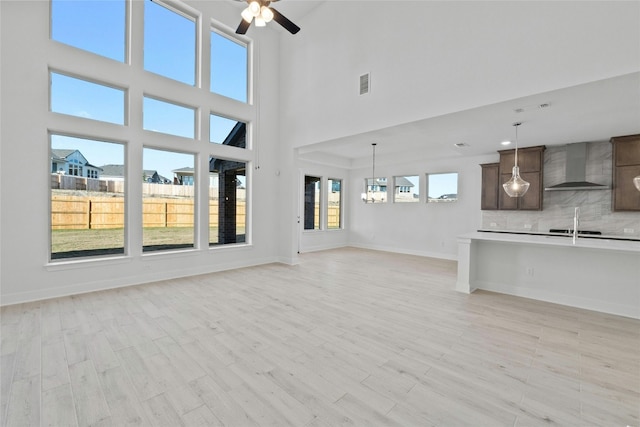 unfurnished living room with light hardwood / wood-style flooring, a high ceiling, and sink