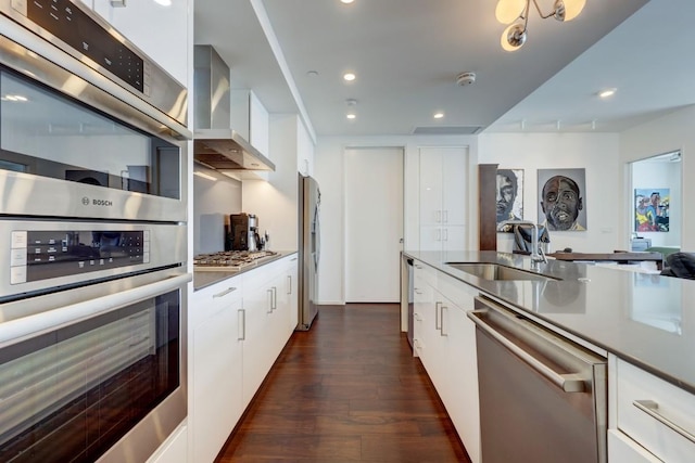 kitchen with white cabinetry, stainless steel appliances, and wall chimney exhaust hood