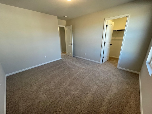 unfurnished bedroom with light colored carpet, a closet, and a spacious closet