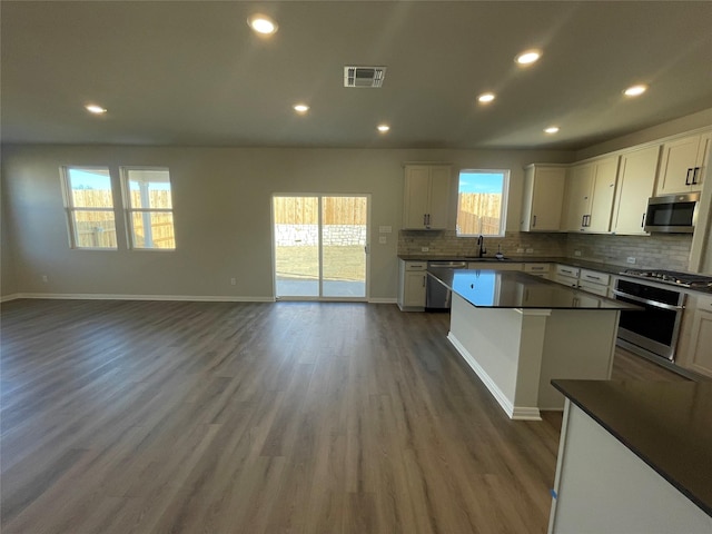 kitchen featuring white cabinetry, stainless steel appliances, backsplash, dark hardwood / wood-style flooring, and sink