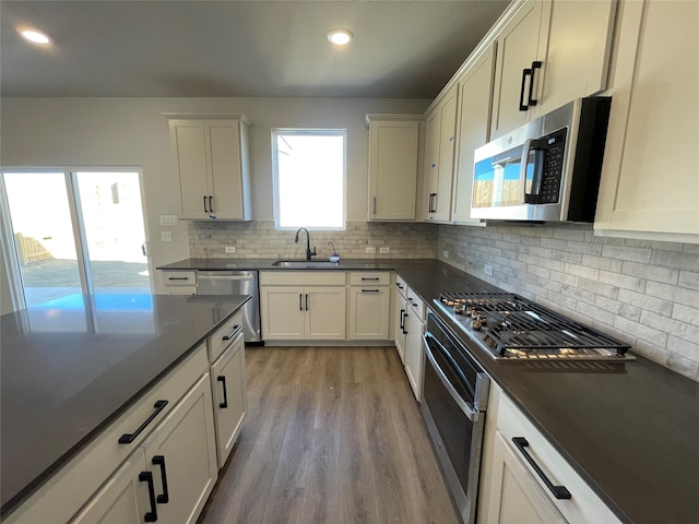 kitchen with white cabinets, sink, stainless steel appliances, and light hardwood / wood-style floors