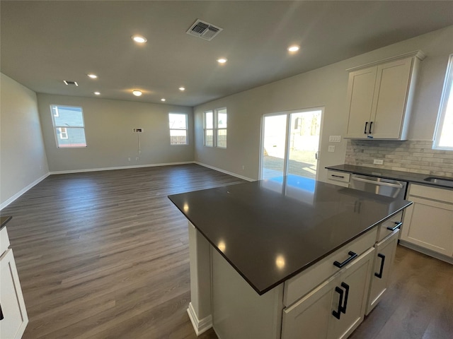 kitchen with dark wood-type flooring, white cabinetry, stainless steel dishwasher, and a center island