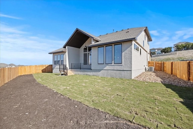 back of house featuring central air condition unit and a lawn