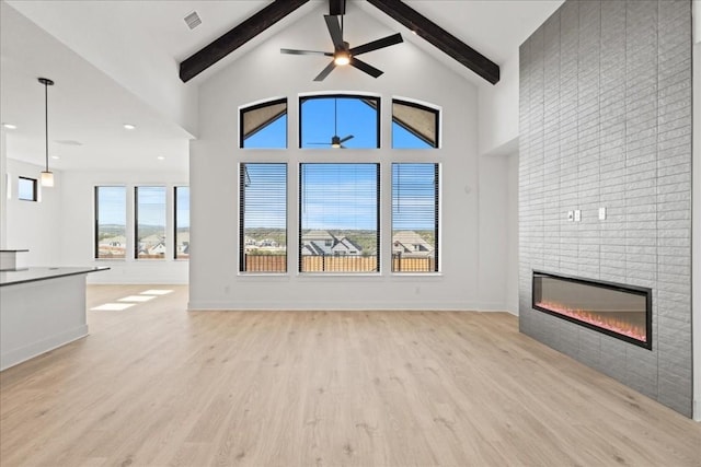 unfurnished living room featuring ceiling fan, beam ceiling, light wood-type flooring, and a fireplace