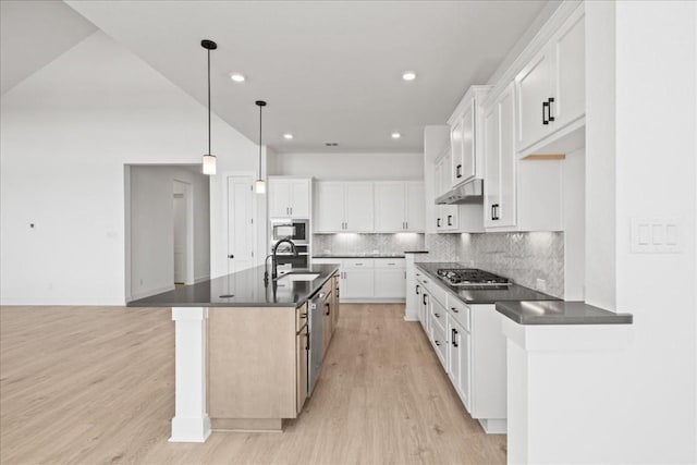 kitchen with a center island with sink, decorative light fixtures, white cabinetry, and appliances with stainless steel finishes