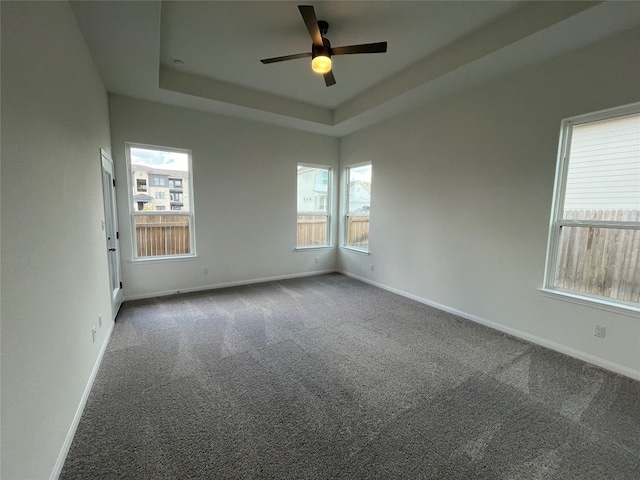 empty room featuring carpet flooring, ceiling fan, and a tray ceiling