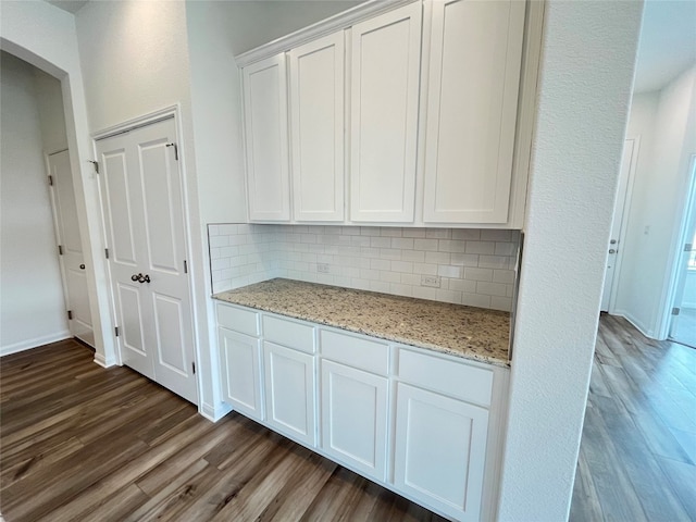 kitchen featuring light stone countertops, white cabinetry, backsplash, and dark hardwood / wood-style flooring