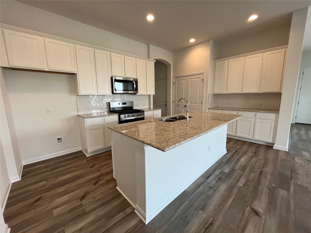 kitchen featuring a center island with sink, sink, appliances with stainless steel finishes, white cabinets, and dark wood-type flooring