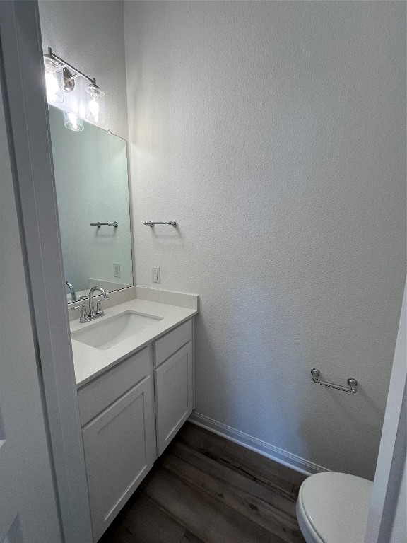 bathroom featuring toilet, vanity, and hardwood / wood-style floors