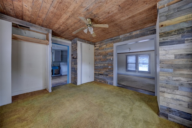 unfurnished bedroom with wooden walls, carpet, wooden ceiling, and ceiling fan