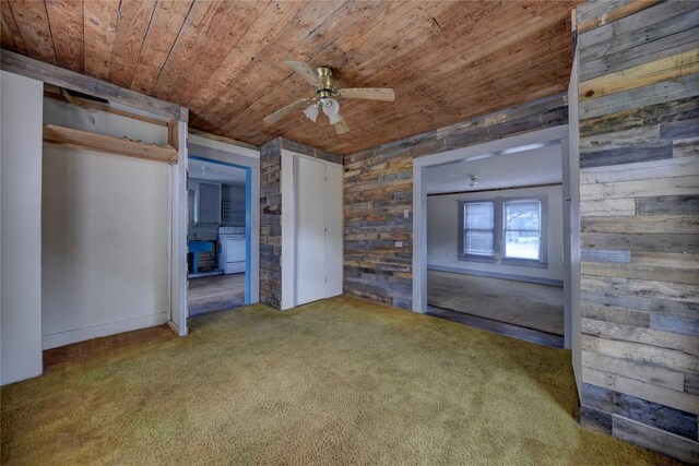 207 S Waco St, Giddings, TX 78942 - unfurnished bedroom featuring wood ceiling, carpet, wooden walls, multiple closets, and ceiling fan