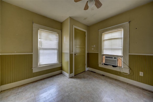 207 S Waco St, Giddings, TX 78942 - spare room featuring wainscoting, plenty of natural light, a ceiling fan, baseboards, and wood walls