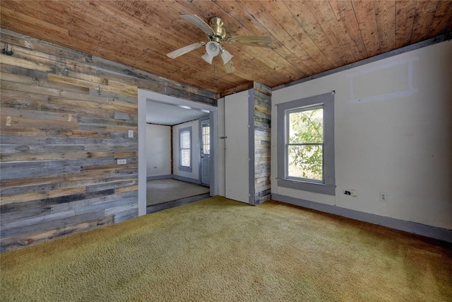 spare room with a wealth of natural light, carpet floors, wood ceiling, and wood walls