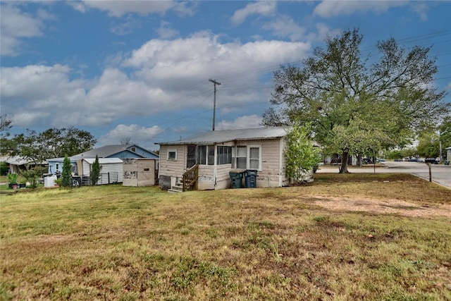 207 S Waco St, Giddings, TX 78942 - back of house with entry steps, a lawn, and a sunroom