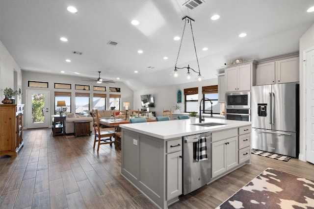 kitchen with stainless steel appliances, ceiling fan, a kitchen island with sink, sink, and pendant lighting